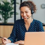 Unternehmensnachfolge Hausverwaltung: Eine freundliche Mitarbeiterin mit Headset führt im Büro ein Telefonat zur Betreuung von Eigentümergemeinschaften während des Übergabeprozesses. Unternehmensnachfolge Hausverwaltung: Eine freundliche Mitarbeiterin mit Headset führt im Büro ein Telefonat zur Betreuung von Eigentümergemeinschaften während des Übergabeprozesses.