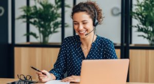 Unternehmensnachfolge Hausverwaltung: Eine freundliche Mitarbeiterin mit Headset f&uuml;hrt im B&uuml;ro ein Telefonat zur Betreuung von Eigent&uuml;mergemeinschaften w&auml;hrend des &Uuml;bergabeprozesses.