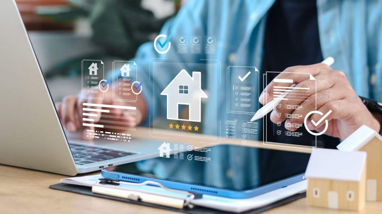 Hausverwaltung verkaufen: Eine Person arbeitet mit einem Tablet, einem Stift und Hausmodellen an der digitalen Strukturierung einer Unternehmensnachfolge.